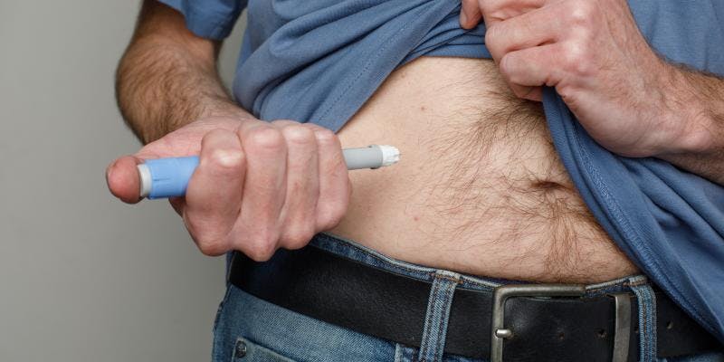 A man injecting himself in the belly with Ozempic