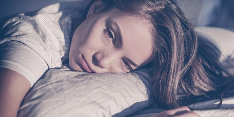 A woman looking sad because she cannot sleep due to her over drinking