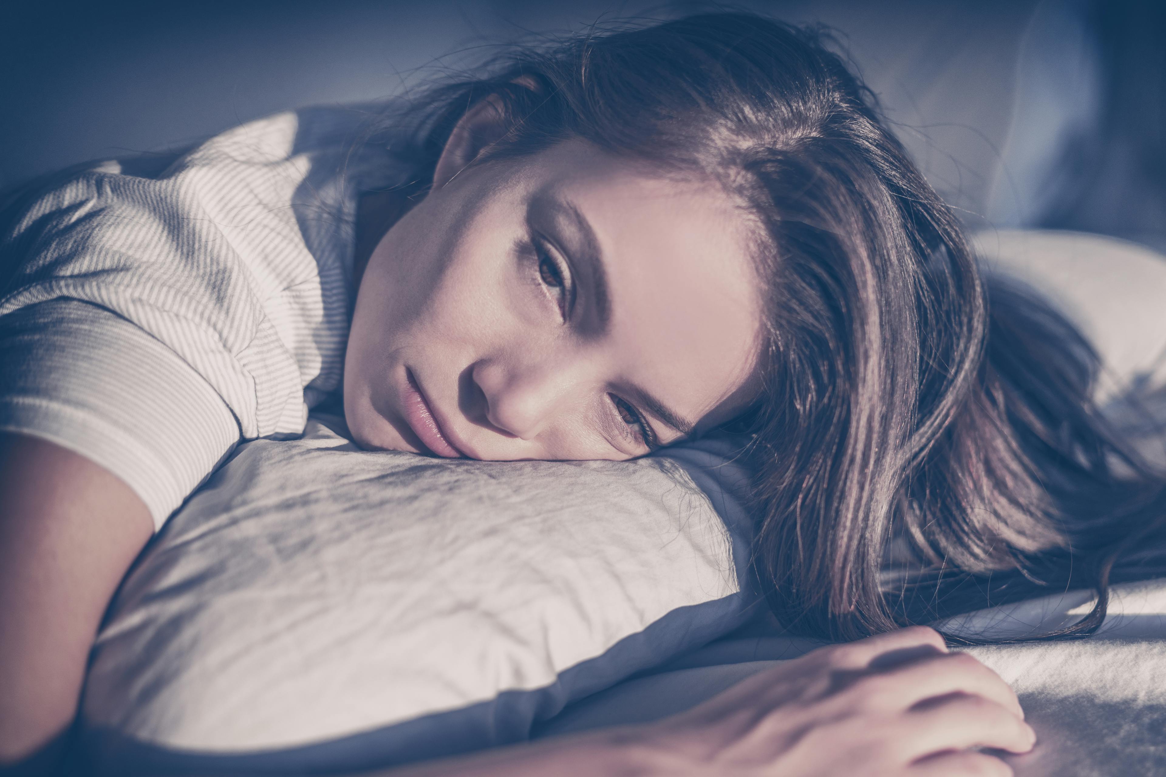 A woman looking sad because she cannot sleep due to her over drinking