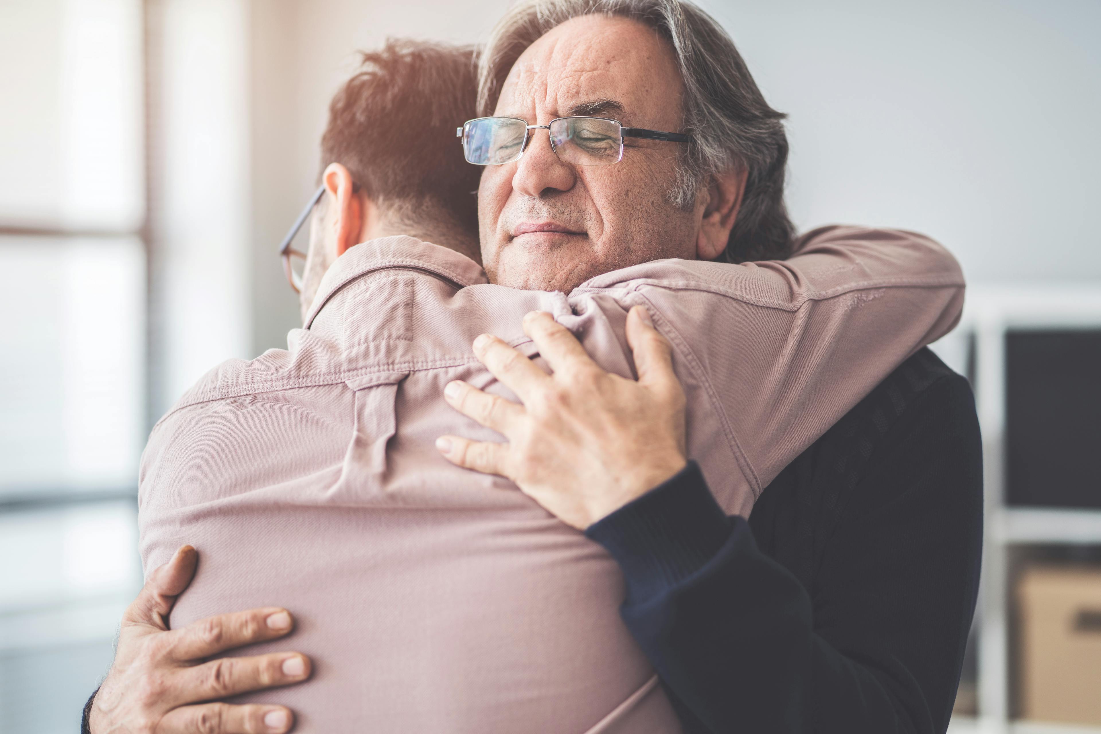 A father and son in a warm, loving, emotion embrace