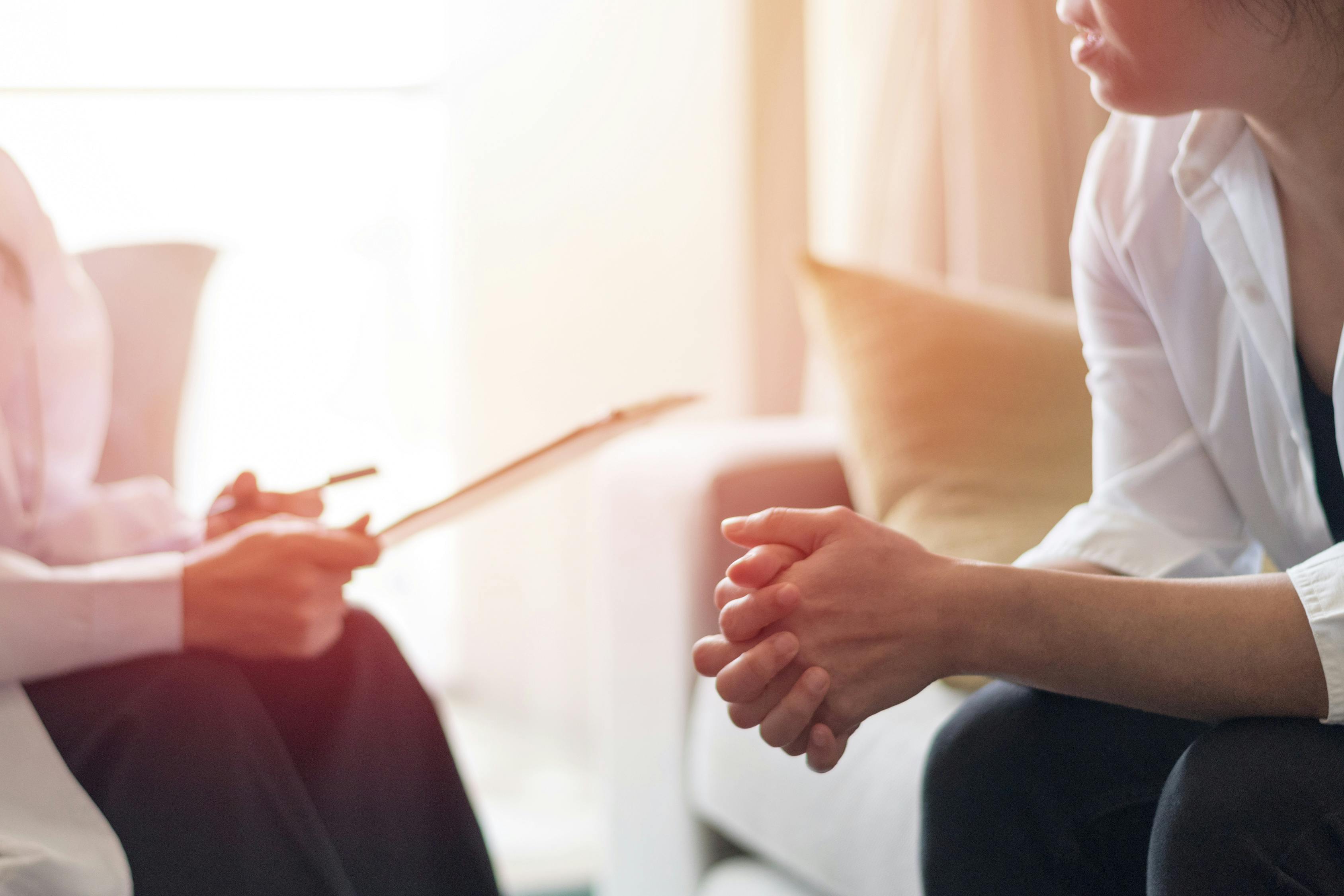 A therapist and a patient talking in a comfortable sun-filled room.